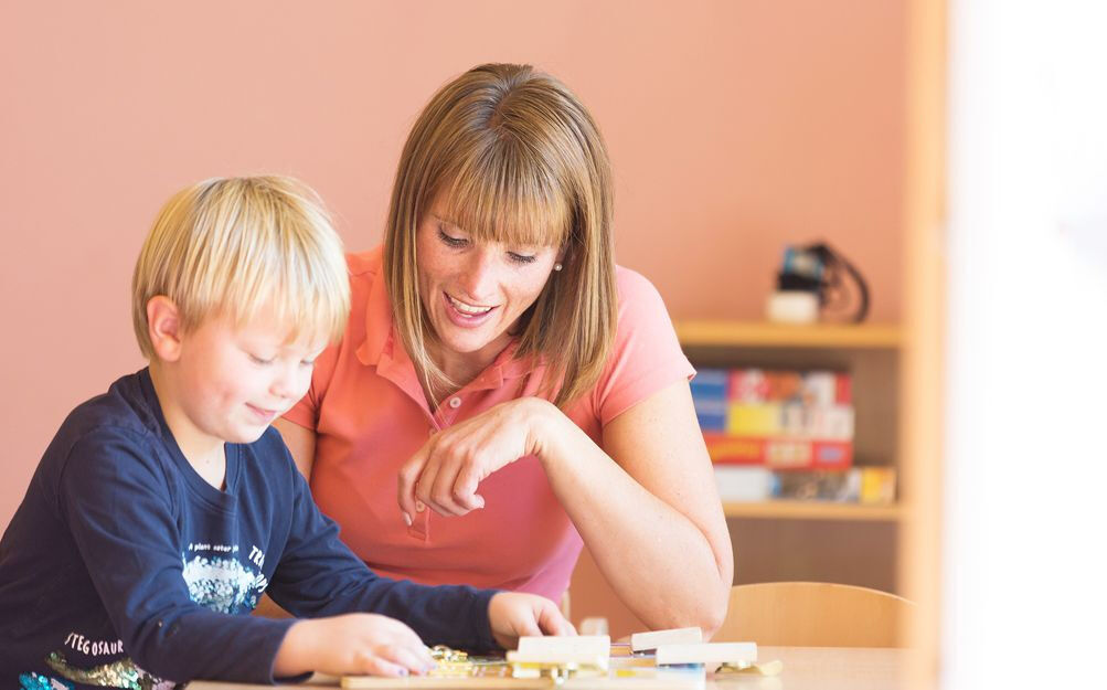 Kindergärtnerin spielt mit Kind am Tisch, Kindergarten, Kita